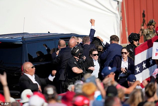 As he was rushed into SUVs, Trump again flashed a fist at his supporters As he was rushed into SUVs, Trump again flashed a fist at his supporters