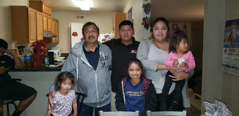 Two men, a woman and several children pose in the family kitchen for a photo. Two men, a woman and several children pose in the family kitchen for a photo.