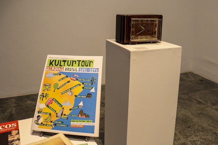 1. Fotografias e relógio de bolso em exposição; 2. Objetos em exposição: livros e relógio de mesa.