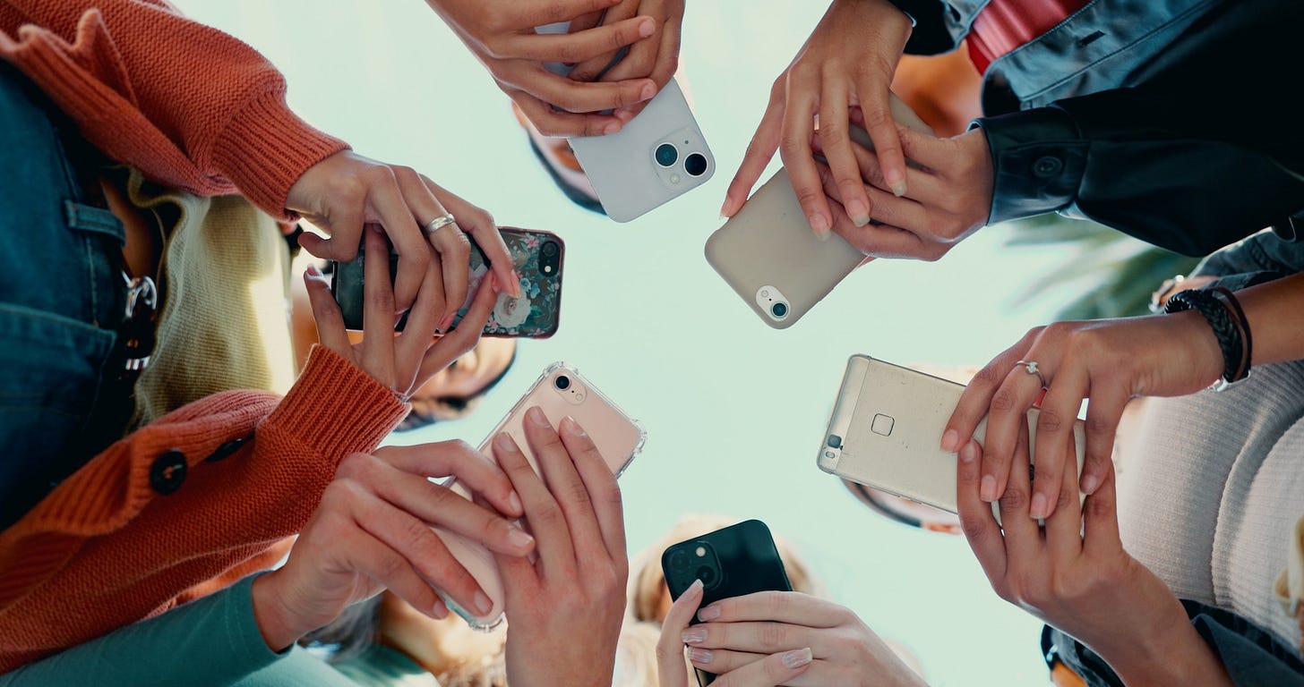 College students holding mobile phones standing in a circle (Image via Shutterstock) College students holding mobile phones standing in a circle (Image via Shutterstock)