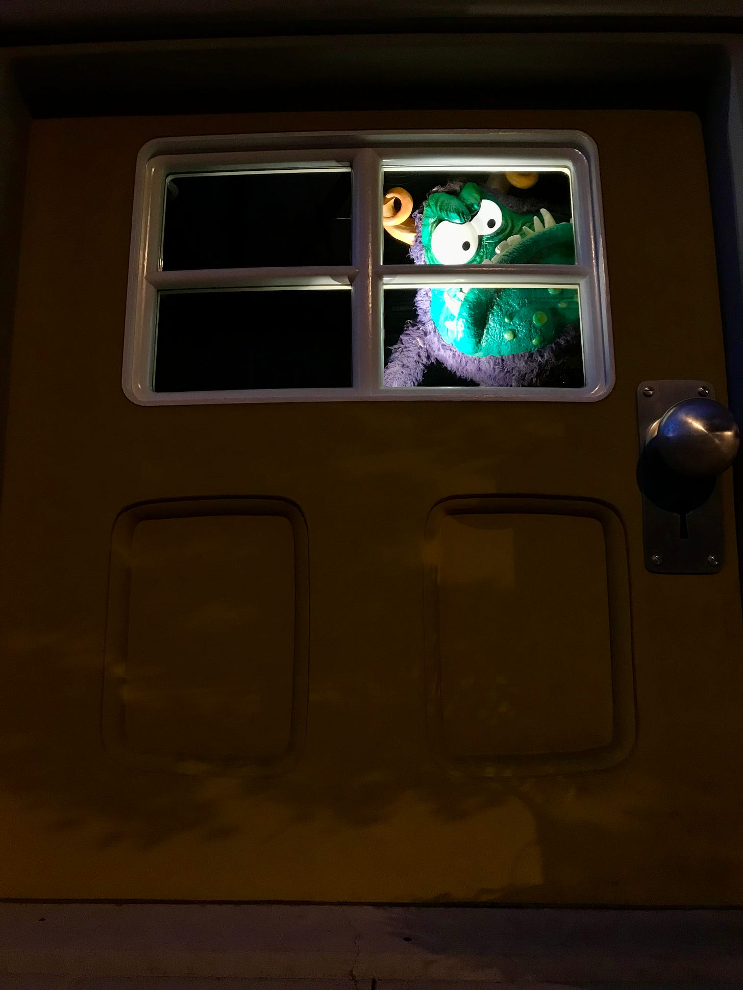 A photo of a giant door with a green monster glaring through its window