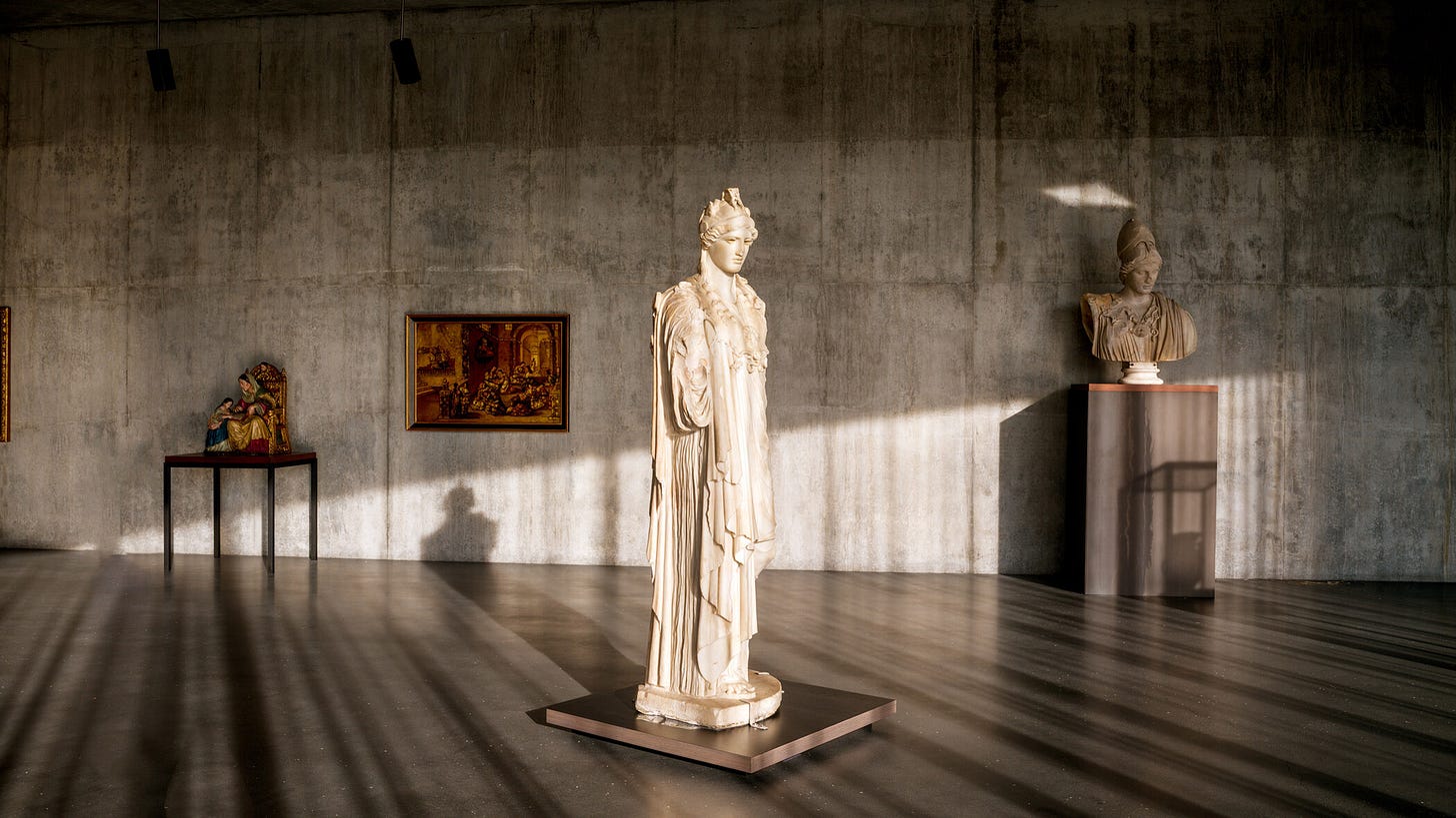A quiet gallery in LACMA’s new Geffen Galleries with concrete walls, soft natural light, and a white classical sculpture centered in the room, surrounded by smaller works on dark pedestals. A quiet gallery in LACMA’s new Geffen Galleries with concrete walls, soft natural light, and a white classical sculpture centered in the room, surrounded by smaller works on dark pedestals.