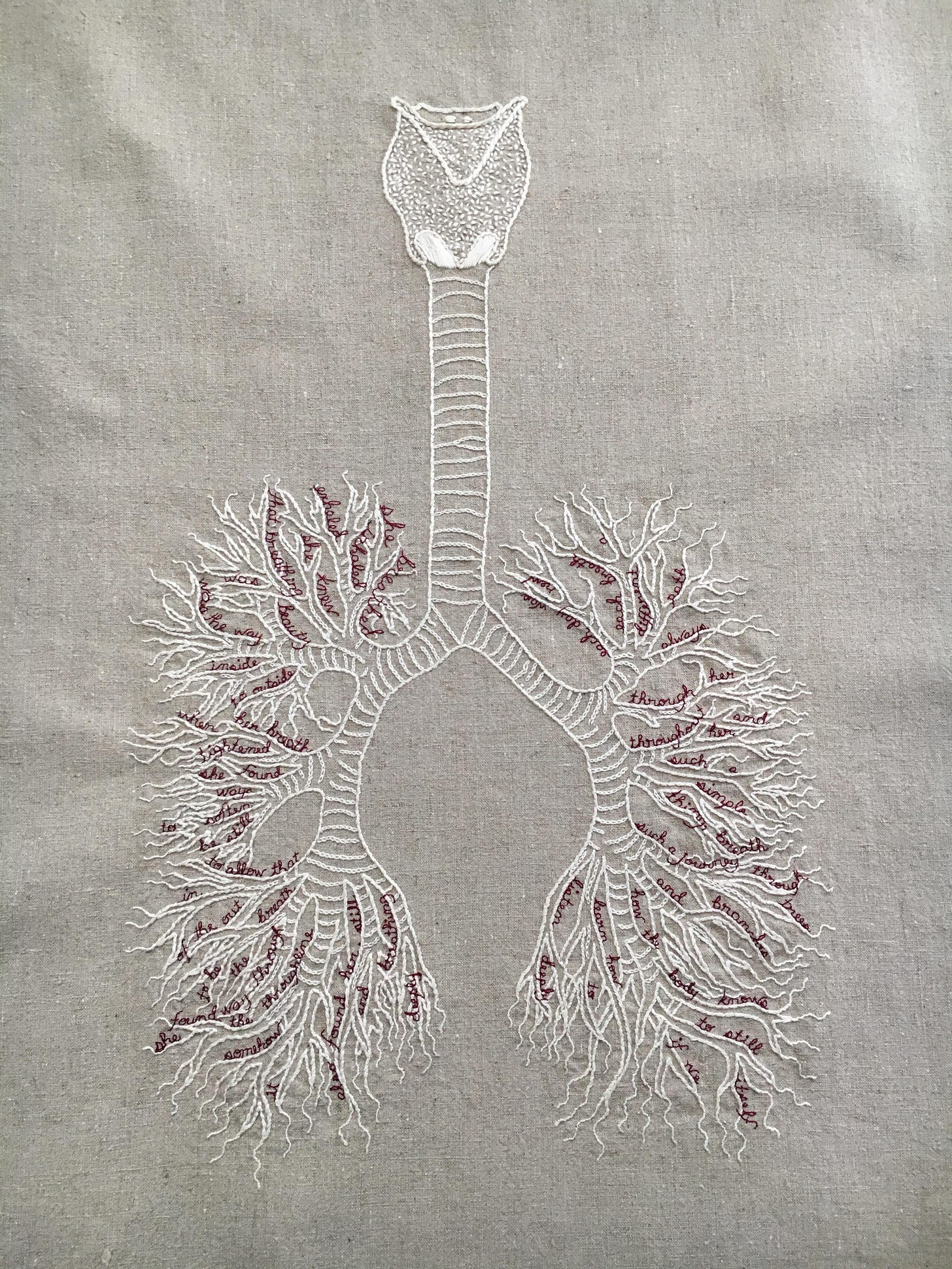 An embroidery on a pale natural linen. There is a bone white diagram of a vocal apparatus, trachea, and bronchi/lungs. In between the branches of the bronchioles are small words embroidered in cursive in thin burgundy thread. They read: she breathed. Inhaled. exhaled. she knew. that breathing. was beauty. was the way. inside. to outside. when her breath. tightened. she found. ways. to soften. be still. to allow that. in. of the out. breath. to be. the. way through. she found the throughline. somehow. it. also found her. still. and breathing. deeply. each day was. new. each breath. a. different. path. always. through her. and. throughout her. such a. simple. thing, breath. such a journey. through. trees. and. branches. how the body knows. to still. itself. if we learn how. to. listen deeply.