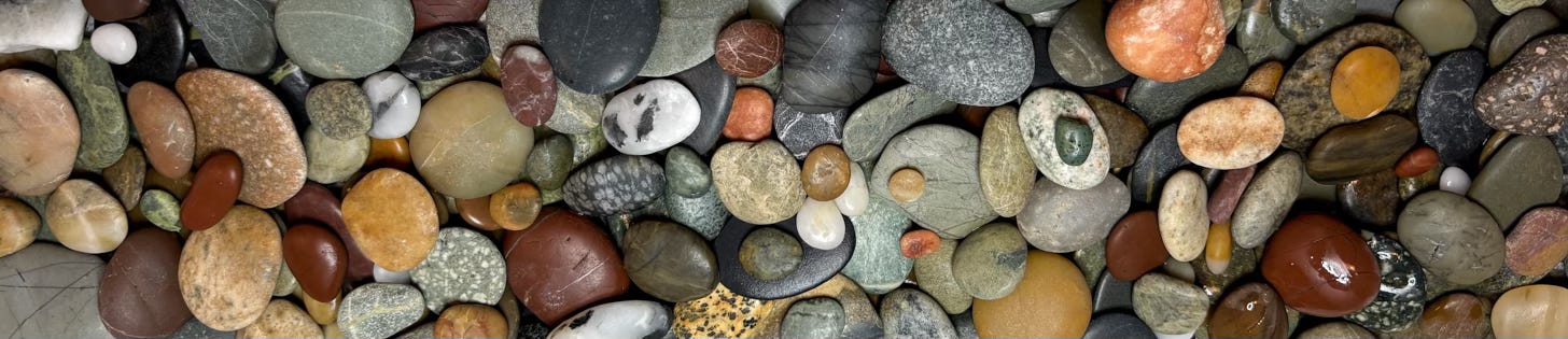 close up of smooth pebbles of varying sizes in tones of green, brown red grey and yellow