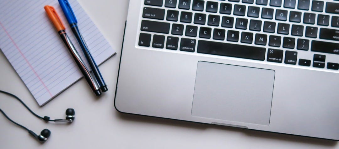 silver laptop computer beside white ruled paper