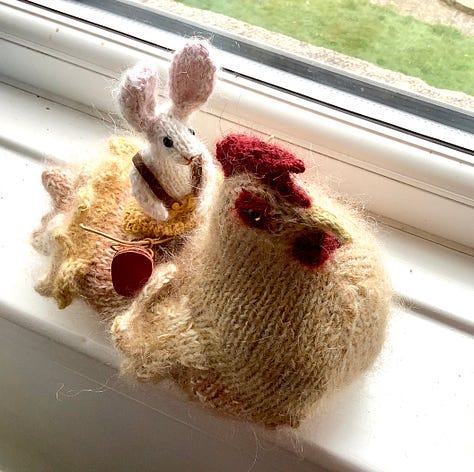 A knitted checking and a knitted rabbit become acquainted, the rabbit is sitting on the chicken and then the chicken is stood up.