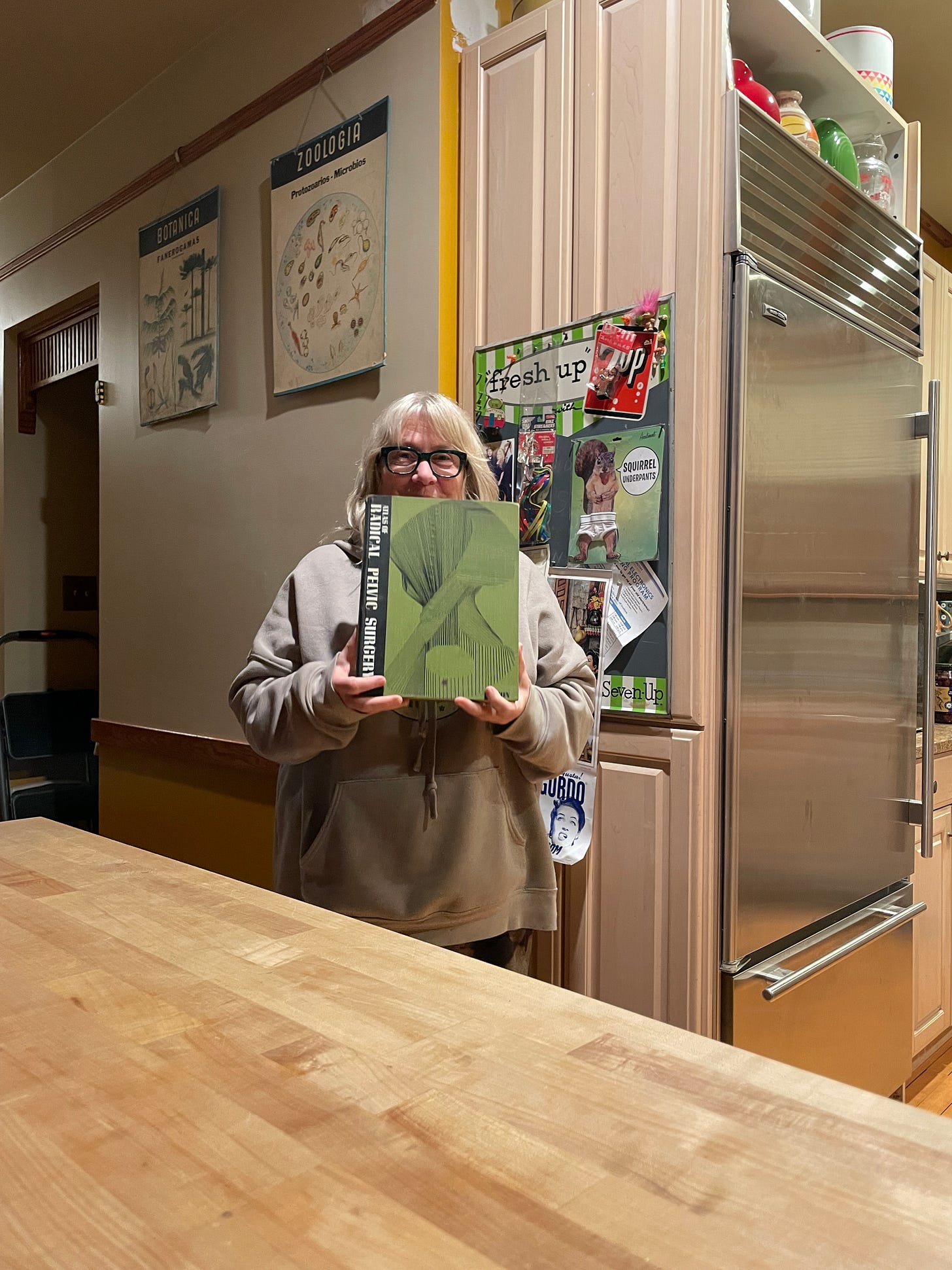My mom holding a vintage book she purchased at a thrift store, called Atlas of Radical Pelvic Surgery.