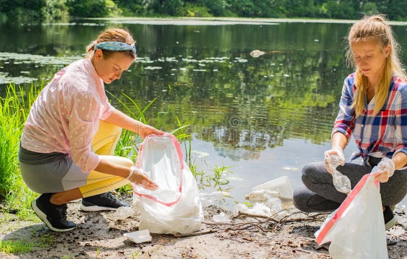 Volunteers Cleaning Garbage Near River. Women Picking Up a Bottle ...