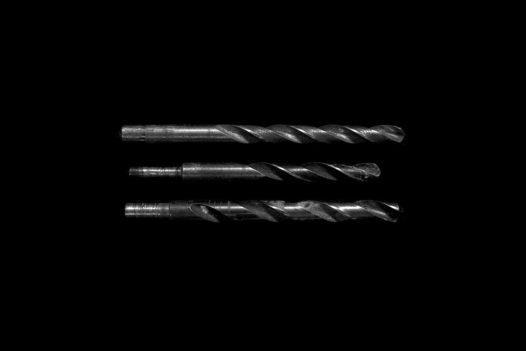 A serious portrait of three drill bits on a black background A serious portrait of three drill bits on a black background