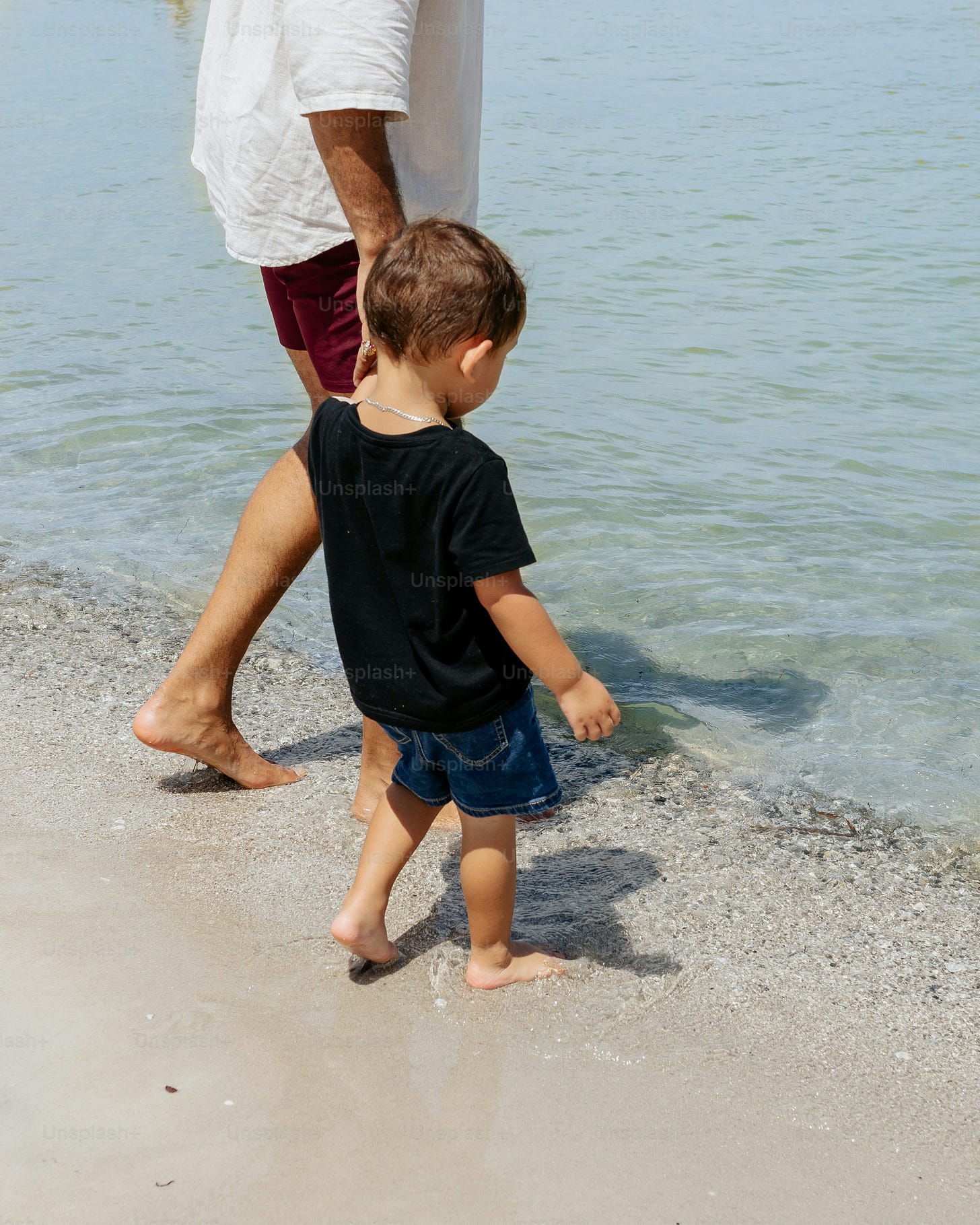 a man and a little boy walking on the beach