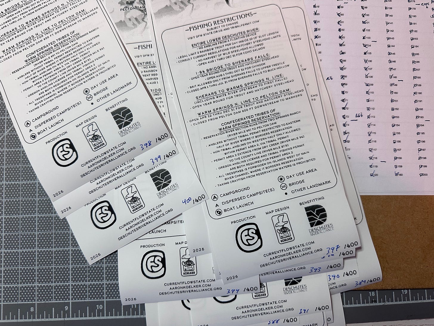 A stack of Lower Deschutes Ribbon Maps being hand-numbered with a checklist noting how many have been numbered so far