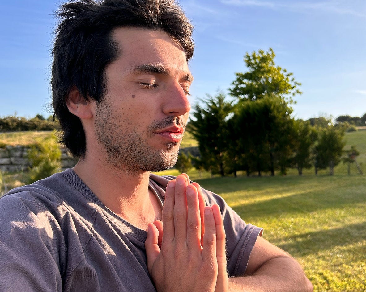 a man with eyes closed holding his hands in the namaste