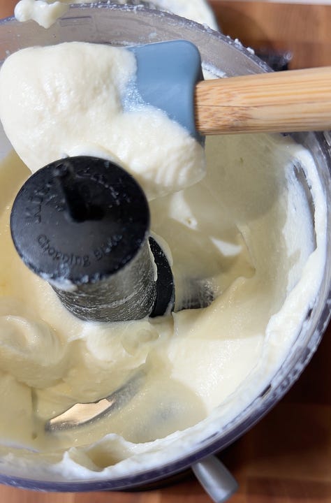 Whipped ricotta in a food processor with a spatula, Finely chopped pistachios and thinly sliced fresh mint being chopped on a wooden cutting board for skewer topping
