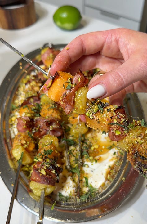 Whipped lime ricotta spread across a silver oval platter, Finished grilled mortadella, cantaloupe, and gnocchi skewers with whipped ricotta and pistachios on a silver platter being topped with hot honey