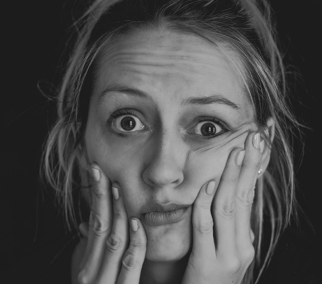 grayscale photo of woman covering her face with her hand