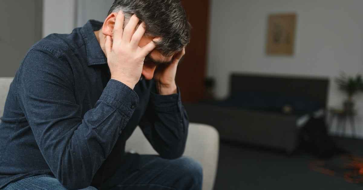 Middle age grey-haired man stressed sitting on sofa at home