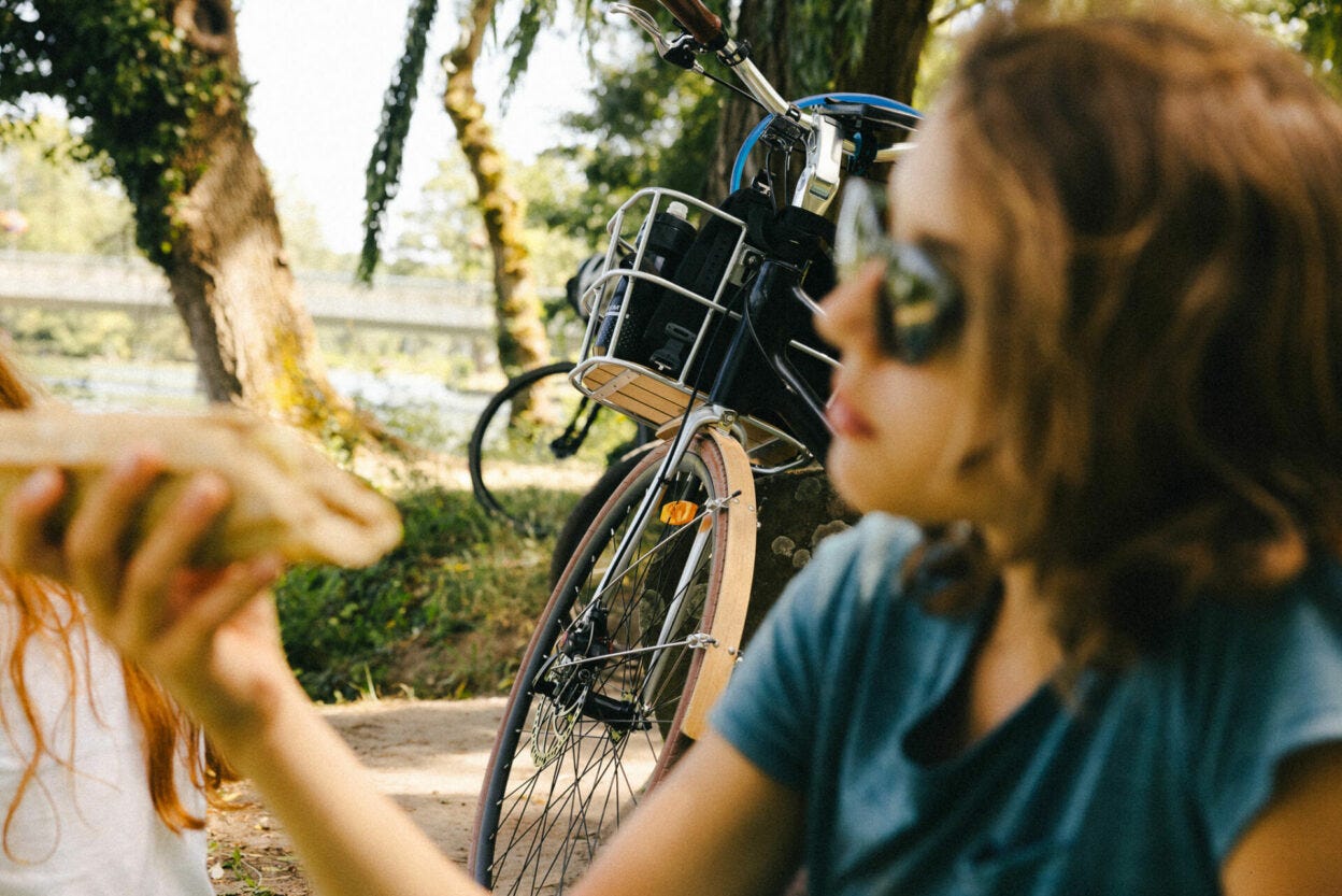 Jeunne ado mangeant un sandwich avec un velo en arriere plan