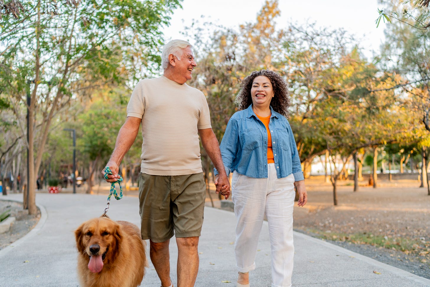 Smiling couple walking their dog in the park
