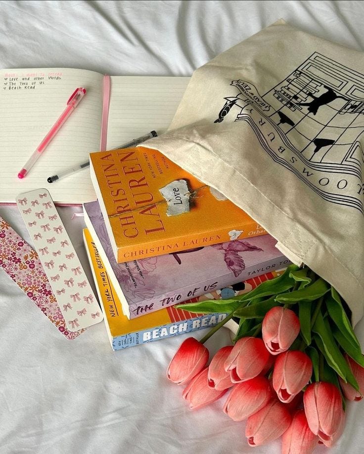 This may contain: a bunch of books sitting on top of a bed next to tulips and a bag
