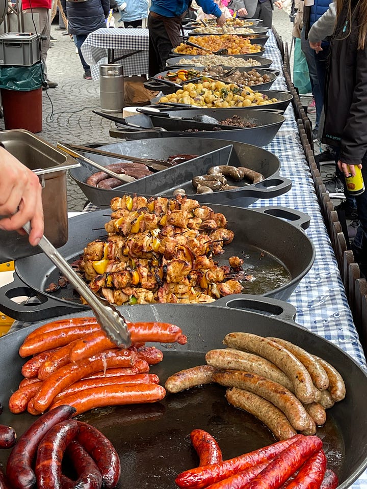 Classic Czech carnival fare — smoky sausages, golden potatoes, and roasted red peppers — the kind of hearty, unfussy food eaten standing up during Masopust celebrations.