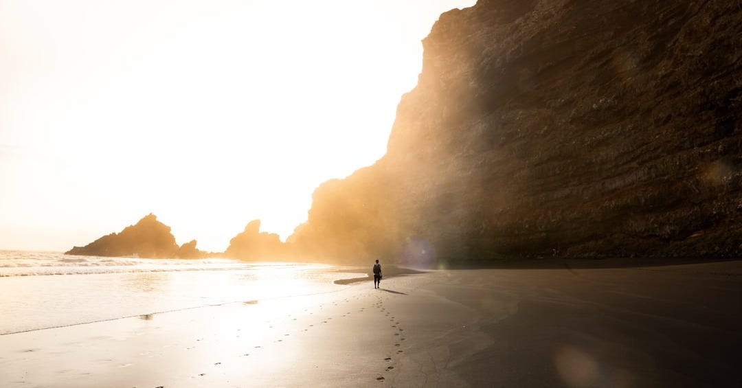 man on shore near rock formation