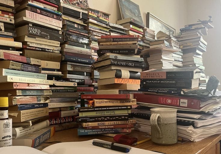 This may contain: a stack of books sitting on top of a wooden table next to a cup and book