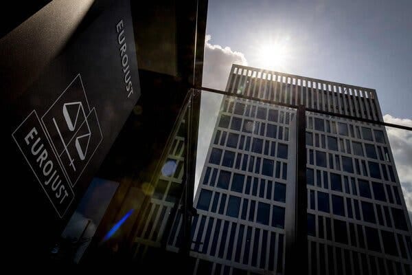 A tall building with a sign in front reading Eurojust. A tall building with a sign in front reading Eurojust.