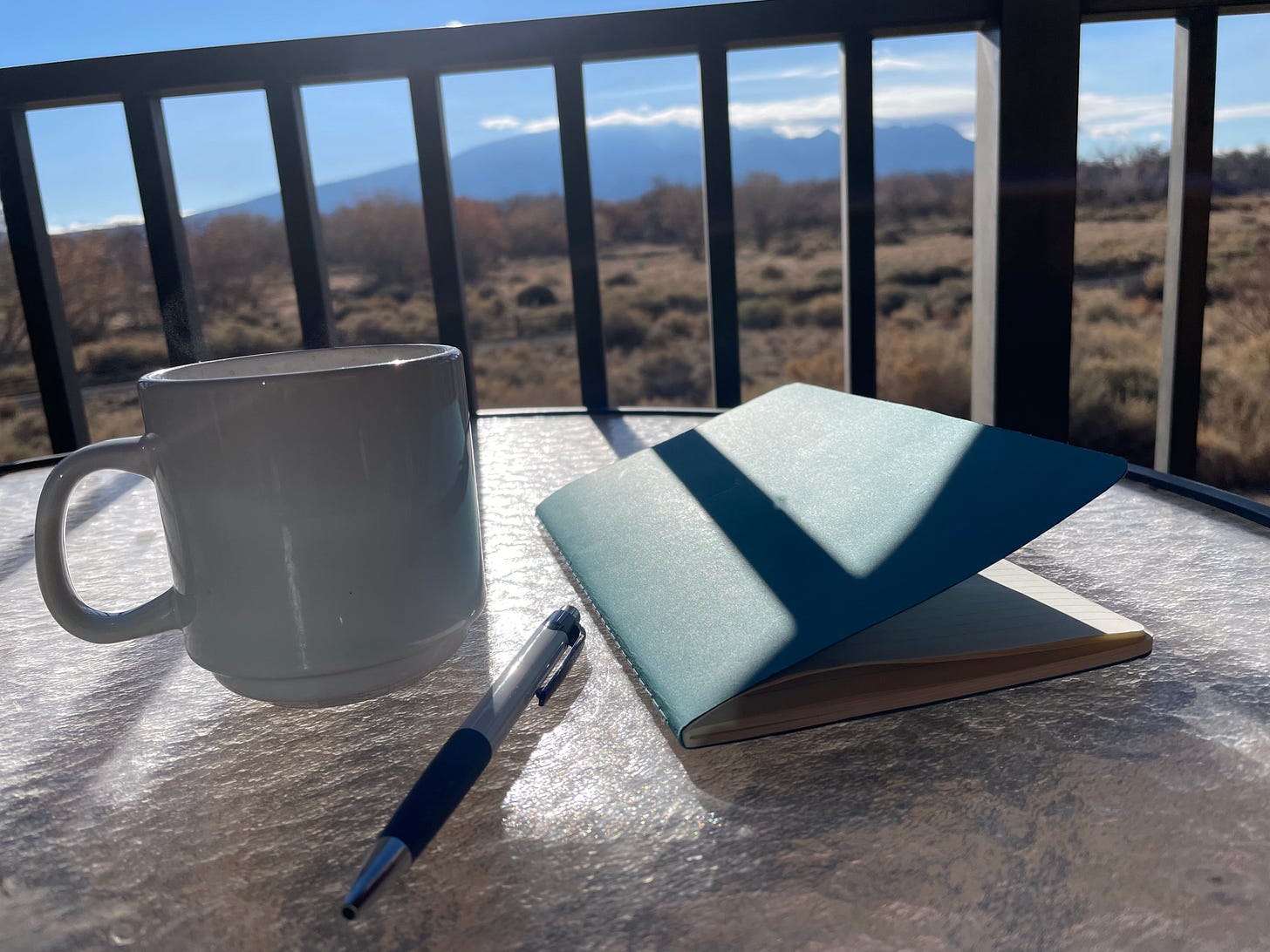 Blue journal on desk with view of Sandia mountains, NM, USA