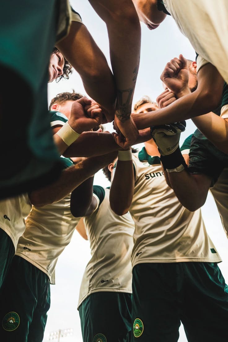 This may contain: a group of men standing around each other in a huddle