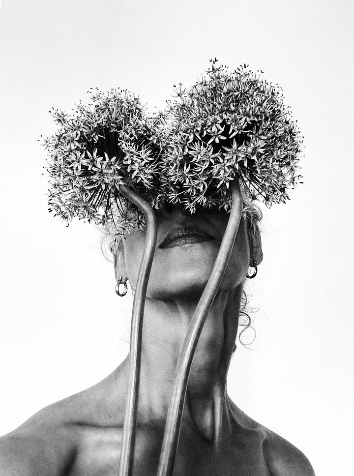 Black-and-white self-portrait of a woman holding two large flower heads in front of her eyes like a mask. The flowers obscure her face, leaving only her lips and the strong lines of her neck and shoulders visible. The image is intimate, surreal, and striking in its simplicity. Black-and-white self-portrait of a woman lying down with her curly hair fanned out, partially covered by deep shadows cast from her own hand. The image plays with light and shadow to create a sense of mystery and emotion, capturing both strength and softness.