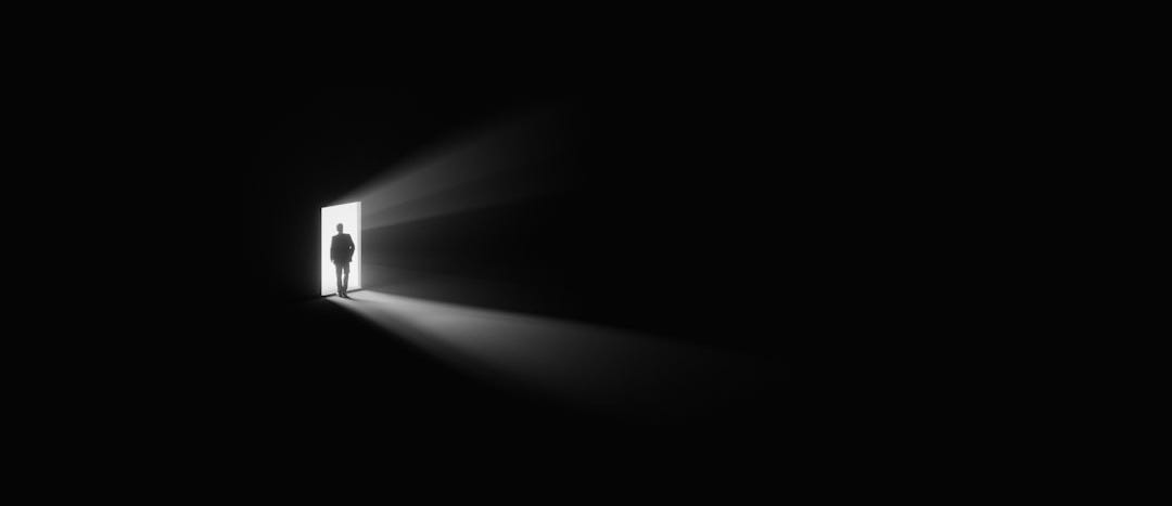 a person standing in a doorway with a light coming through it