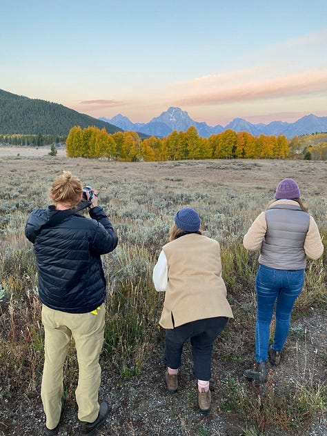Images from Jackson Wild Summit in Grand Teton National Park in Wyoming. Graham looking through the viewfinder of a camera on a tripod. 3 people taking photos of the mountains at sunrise. 4 people sitting on stage at a Summit workshop.