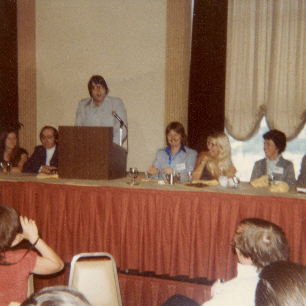 Low quality photo from the World Fantasy Convention held in Providence, RI in 1979. Stephen King speaks from the lectern. Next to him sits a young Michael Whelan with his wife Audrey Price.