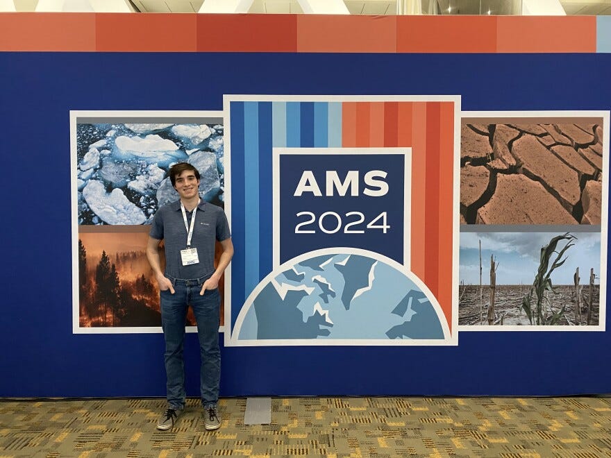 UD Student Thomas Florio stands in front of an AMS sign poster wall