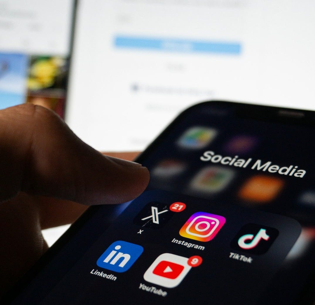 A person holding a smart phone with social media on the screen