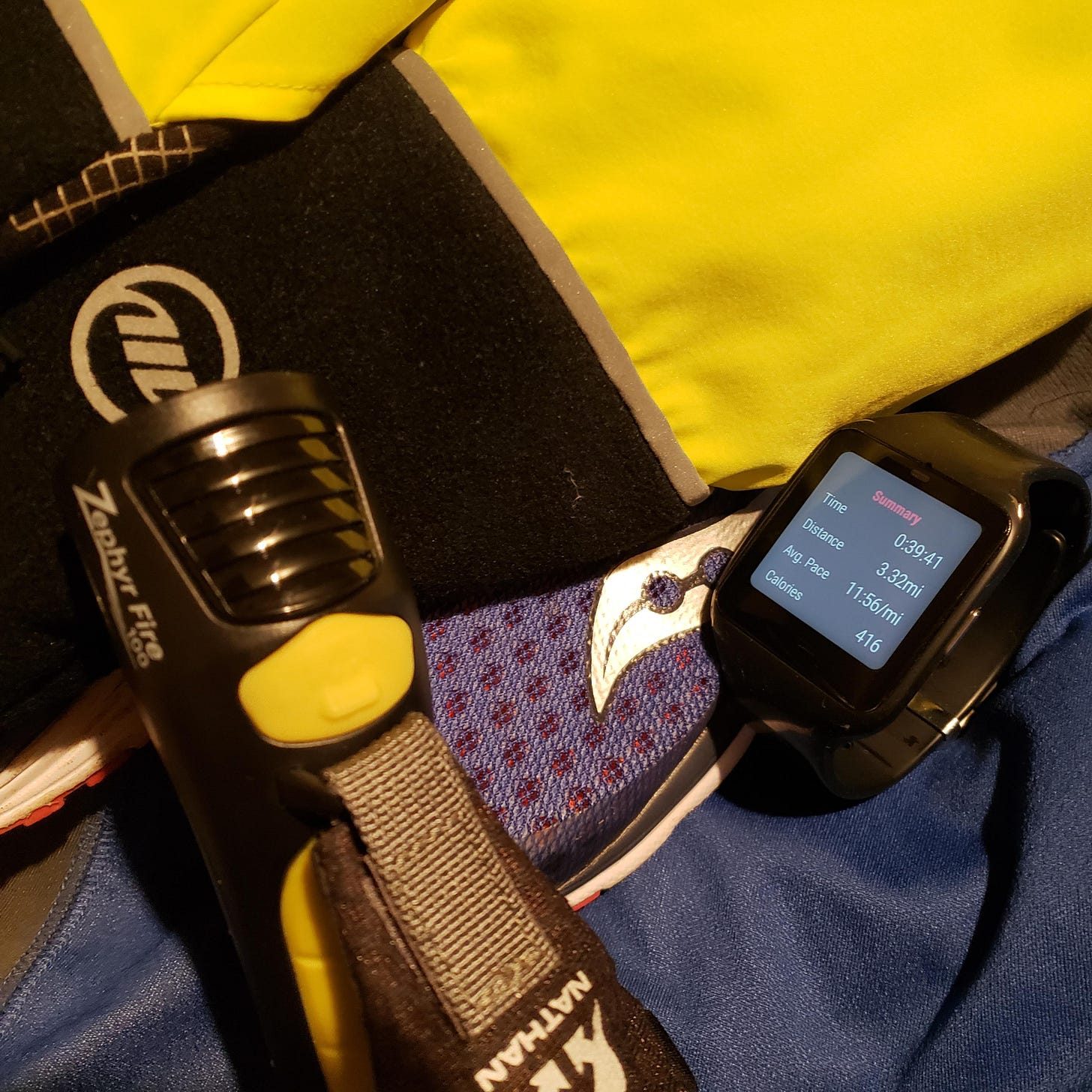 Sony smart watch sitting alongside winter running equipment - hi viz gloves, flashlight, and jacket