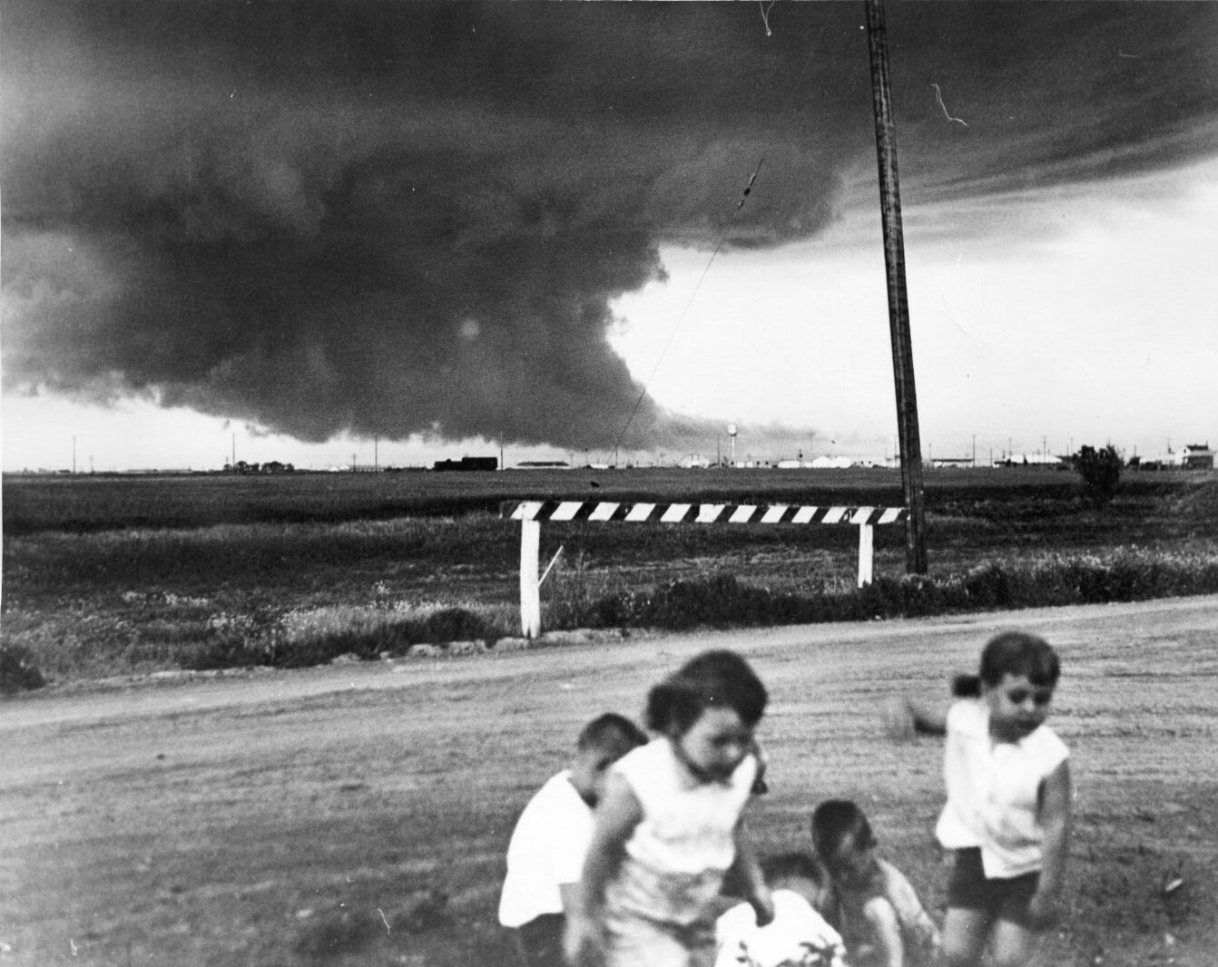 Una de las fotografías más inquietantes del 20 de junio de 1957: niños jugando ajenos al peligro, mientras la nube de embudo mortal se aproxima al fondo (Alf T. Olsen)