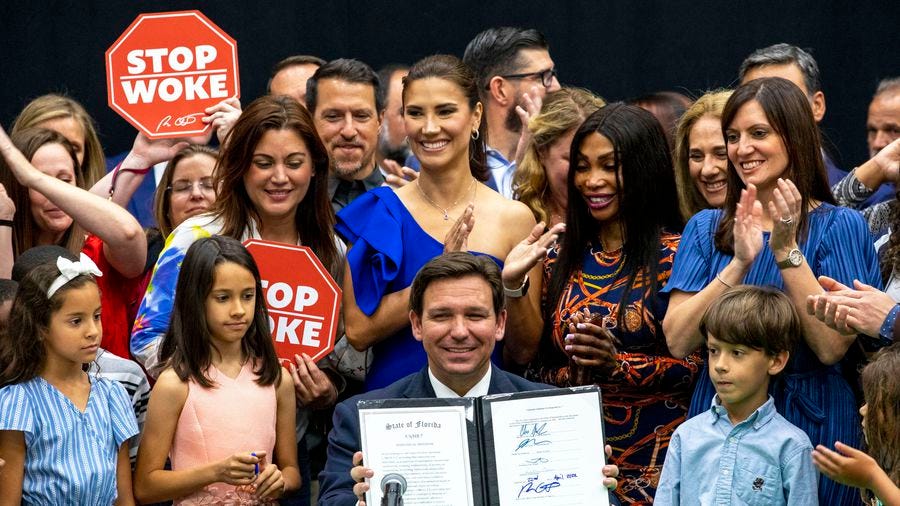 DeSantis signs 'stop woke' act, Disney bills next to a stage full of  supporters