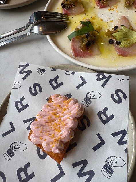 A finger bun with pink icing, Plastic Budgie styled at a bookshop, and a snack with pink dip.