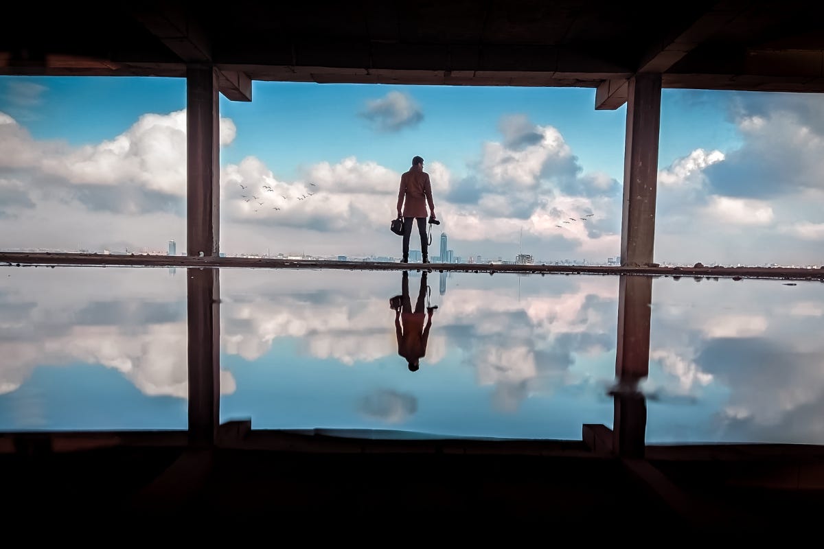 A man overlooking city skyline with reflection of sky and himself