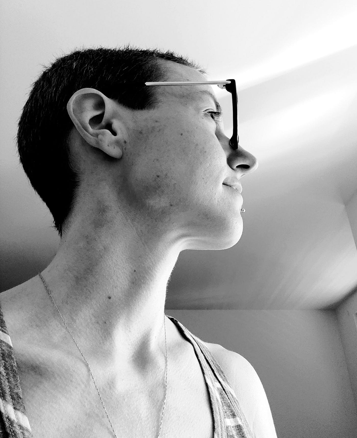 The black-and-white picture shows the author, a young woman, with short hair and glasses, looking towards something outside of the picture.