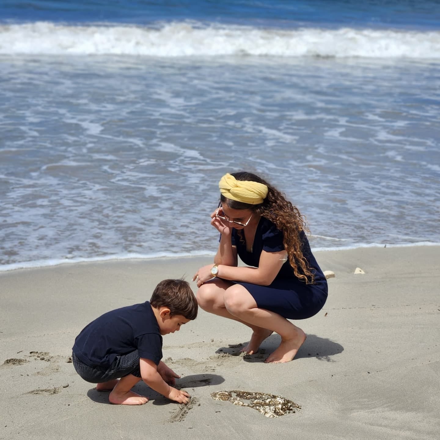 May be an image of 2 people, baby, ocean and beach