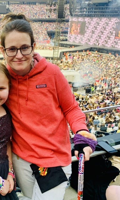 A white woman with a cane standing next to a child. They are in front of a stadium setting up for the show. A white woman with a cane standing next to a child. They are in front of a stadium setting up for the show.