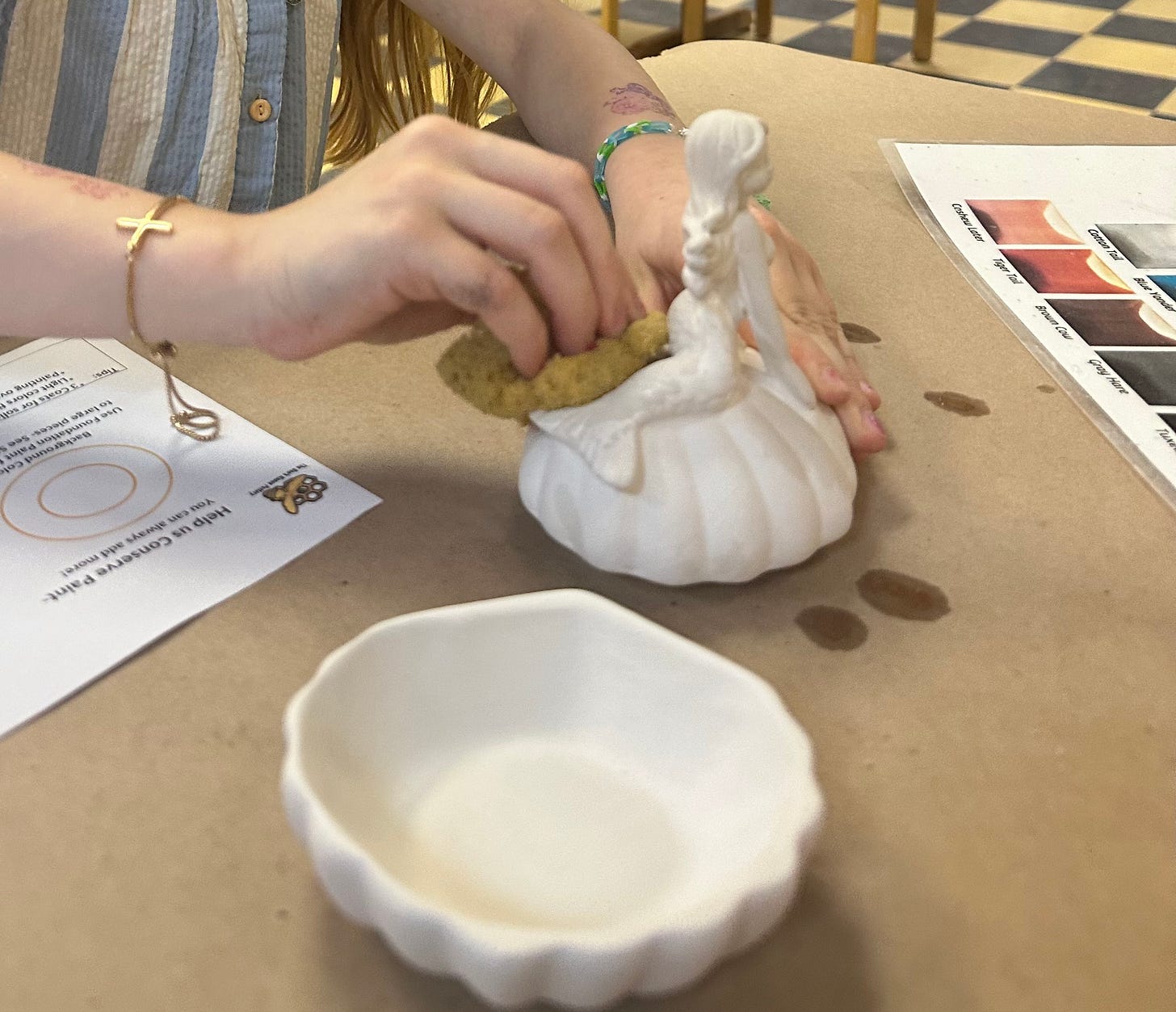 Girl sponging off an unpainted ceramic mermaid