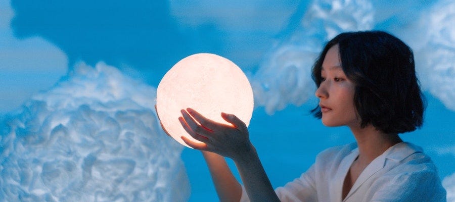 Woman looking into glowing ball Woman looking into glowing ball