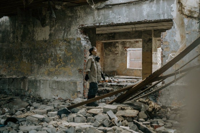 A child with chin up standing amidst a demolished structure looking for hope