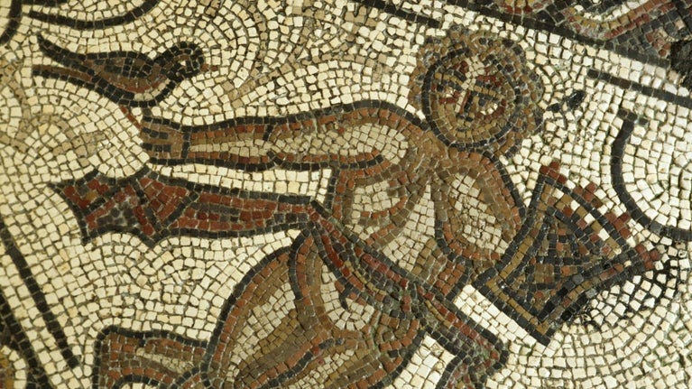 Close up of the figure of 'Spring' with a basket of flowers in one hand a small bird in the other at Chedworth Roman Villa, Gloucestershire