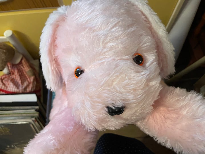 A large pink plush dog seen from the front and side.