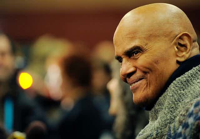 A man wearing a green sweater smiles. A man wearing a green sweater smiles.