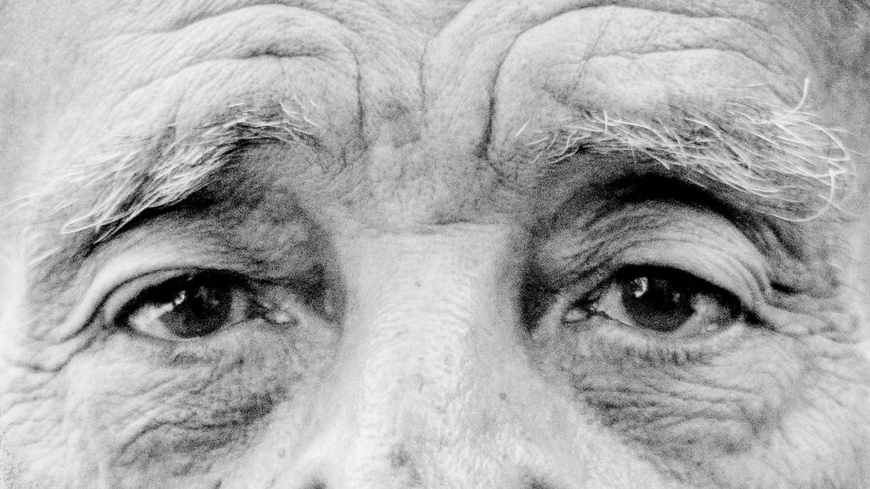 Foto em preto e branco mostrando em detalhe os olhos de um homem idoso caucasiano.